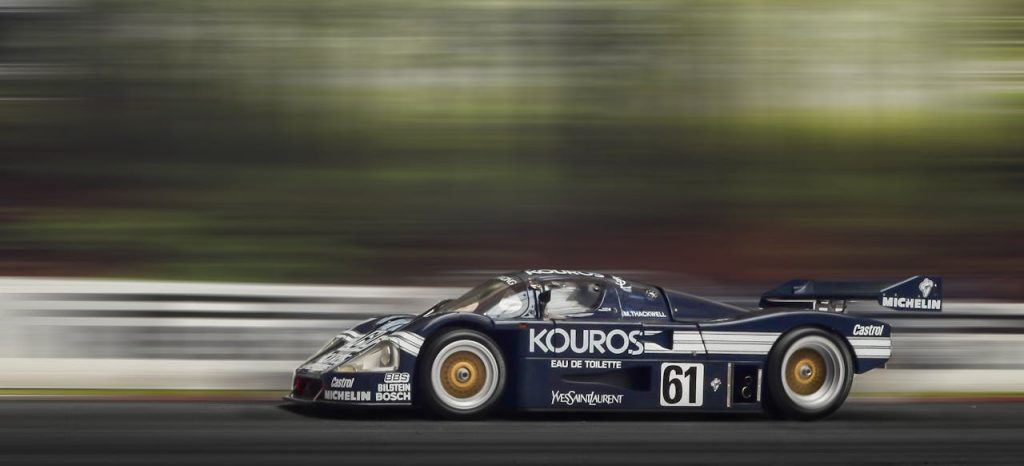 A sleek race car speeds around the track, showcasing motion blur and dynamic movement.